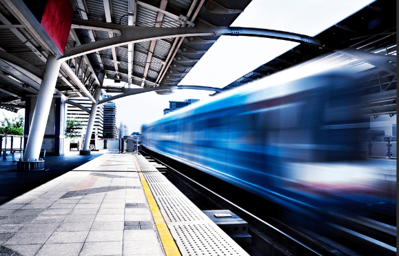 A passenger train speeds by on a track next to the station platform.