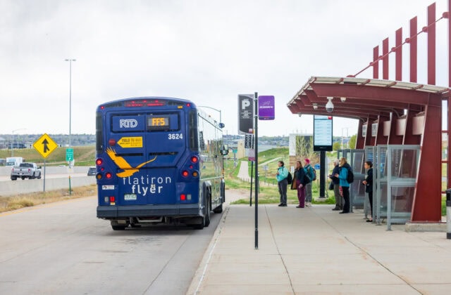 Image of RTD Flatiron Flyer parked at US 36 Broomfield Station to pick up passengers. Passengers waiting in line to enter the bus.