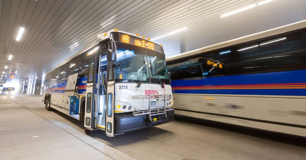 Two RTD regional express buses at an underground gate. The front bus is labeled AB via E-470