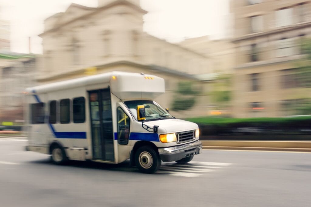 A shuttle bus drives down a city street.