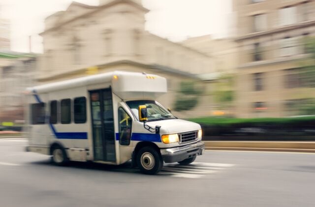 A shuttle bus drives down a city street.